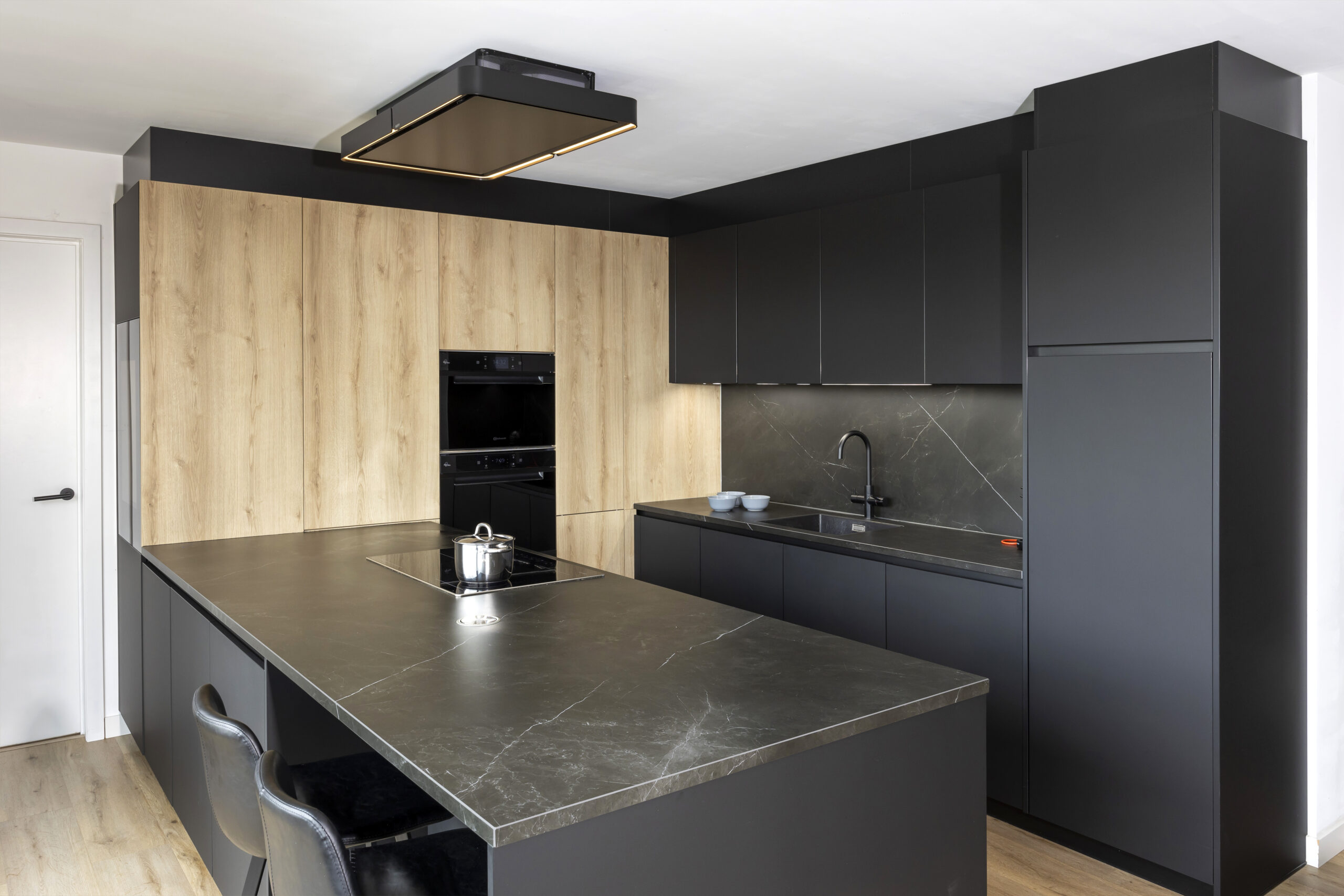 strakke zwarte moderne keuken met houttoets novy dampkap greeploos wijnkoeler liebher keramisch werkblad